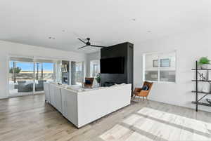 Living area with light wood-style floors, ceiling fan, and recessed lighting