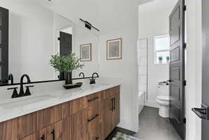 Full bath with double vanity, a bathtub, and tile patterned floors