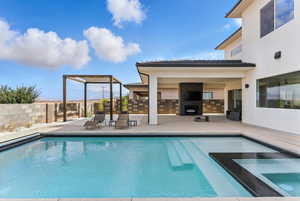 View of swimming pool with a patio area, an outdoor fireplace, and a pool with connected hot tub