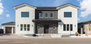 View of front of property featuring stone siding, a garage, a standing seam roof, concrete driveway, and stucco siding