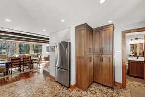 Kitchen featuring freestanding refrigerator, recessed lighting, brown cabinetry, and wood finished floors