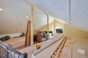 Living room featuring vaulted ceiling above garage