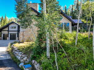 View of side of property with driveway, stone siding, and a garage