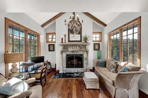 Living room featuring a chandelier, hardwood / wood-style flooring, and a stone fireplace