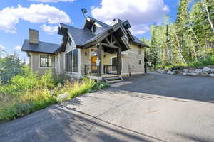 View of front of property with a chimney, driveway, and a porch