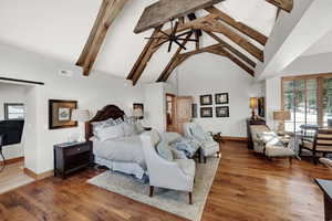 Bedroom with beam ceiling, high vaulted ceiling, and wood finished floors