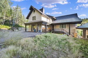 View of front of property featuring covered porch, a chimney, and a shingled roof