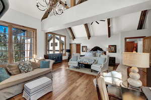 Bedroom featuring high vaulted ceiling, a chandelier, wood-type flooring, and beamed ceiling