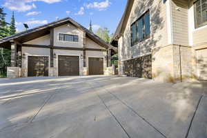 View of side of property with stone siding, concrete driveway, and a garage