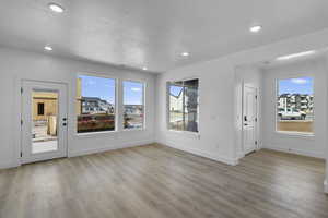 Unfurnished living room featuring light wood finished floors, recessed lighting, and a textured ceiling