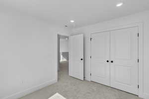 Unfurnished bedroom featuring light colored carpet, recessed lighting, and a closet