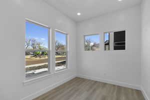 Empty room with light wood finished floors and recessed lighting