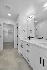 Bathroom with double vanity, a walk in closet, recessed lighting, and tile patterned floors