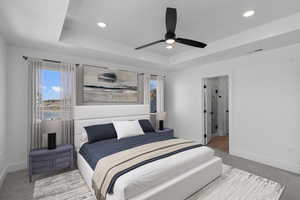 Carpeted bedroom featuring a tray ceiling, recessed lighting, and ceiling fan