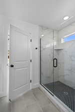 Full bathroom with a marble finish shower and tile patterned flooring