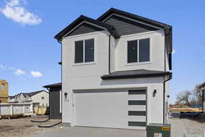 View of front of house with an attached garage, concrete driveway, and stucco siding