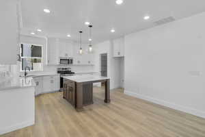 Kitchen with appliances with stainless steel finishes, white cabinetry, tasteful backsplash, and recessed lighting