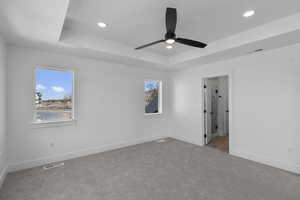Unfurnished bedroom featuring a tray ceiling, recessed lighting, carpet flooring, and ceiling fan