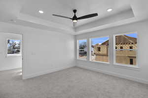Spare room featuring a tray ceiling, light carpet, recessed lighting, and ceiling fan
