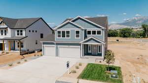 View of front facade with board and batten siding, a garage, covered porch, a shingled roof, and concrete driveway