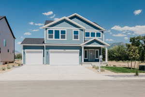 View of front facade with covered porch, board and batten siding, concrete driveway, a garage, and a mountain view