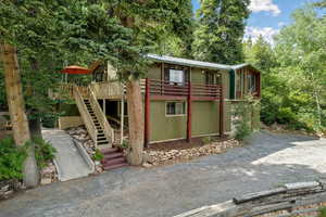 View of front of home with stairs, a metal roof, and a wooden deck