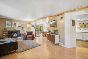 Living area featuring light wood-style floors and a stone fireplace