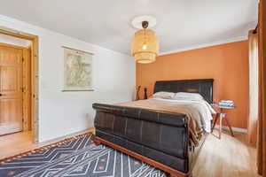 Bedroom featuring wood finished floors and crown molding