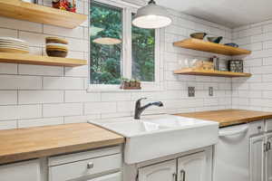 Kitchen with wood counters, open shelves, decorative backsplash, and dishwasher
