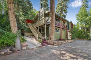 Rear view of house featuring stairs, a wooden deck, and driveway