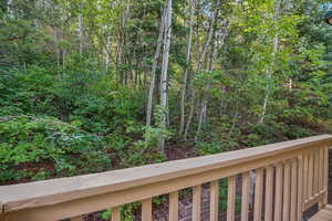Wooden terrace featuring a wooded view