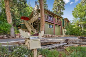 Back of house featuring stairs and a wooden deck