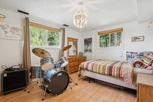 Bedroom with wood finished floors, multiple windows, and a chandelier