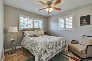 Bedroom with multiple windows, wood finished floors, and a ceiling fan