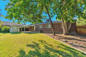 Back of house with brick siding, a storage shed, and a patio area