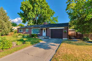 Single story home with brick siding, driveway, an attached garage, and a chimney