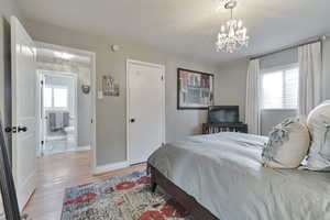 Bedroom featuring a chandelier, multiple windows, and light wood-type flooring