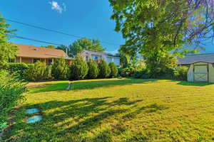 View of green lawn featuring a storage unit