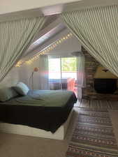 Bedroom featuring access to exterior, vaulted ceiling, and carpet flooring