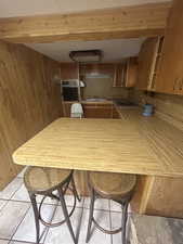 Kitchen with wooden walls, oven, open shelves, a peninsula, and gas cooktop