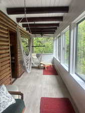 Sunroom featuring ceiling fan and beam ceiling