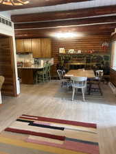 Dining space featuring light wood finished floors, a wood ceiling with exposed beams, rustic walls, and baseboard heating
