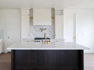 Kitchen featuring wood finished floors, white fridge with ice dispenser, white cabinets, and light stone countertops
