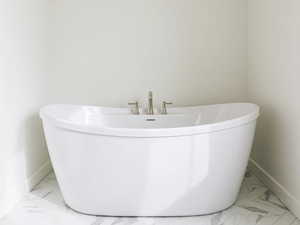 Full bath featuring marble finish flooring and a freestanding tub