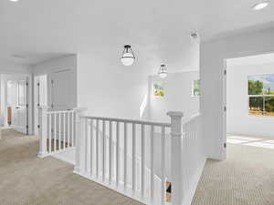 Corridor with an upstairs landing, carpet flooring, and recessed lighting