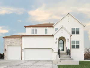 View of front facade with concrete driveway, an attached garage, stucco siding, and stone siding