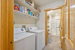 Laundry area with washer and clothes dryer and light tile patterned floors