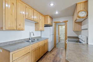 Kitchen featuring white appliances, a textured ceiling, light brown cabinetry, recessed lighting, and wood finished floors