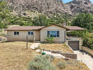 Ranch-style home featuring driveway, an attached garage, brick siding, a chimney, and a mountain view