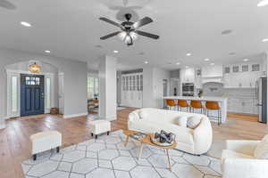 Living area with light wood-type flooring, recessed lighting, arched walkways, and ceiling fan